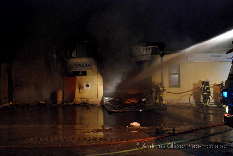 DSC_0103.JPG - Vid 01.30 larmades Räddningstjänsten från flera stationer samt ambulans och polis till Helsingborgsvägen i Ängelholm där man hade en fullt utvecklad brand i en byggnad som beräknas vara 30 meter bred och 100 meter lång, i byggnaden finns bland annat ett företag som sysslar med fyrverkerier och en bilverkstad. Så man vet inte om där finns gasolflaskor. En hel del fyrverkerier har smällt av. Man har ännu inte kontroll över branden då det även är svårt att få fram vatten eftersom brandposten har frusit fast. Ingen person ska ha skadats i branden.