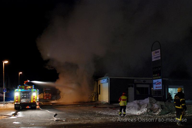 DSC_0113.JPG - Vid 01.30 larmades Räddningstjänsten från flera stationer samt ambulans och polis till Helsingborgsvägen i Ängelholm där man hade en fullt utvecklad brand i en byggnad som beräknas vara 30 meter bred och 100 meter lång, i byggnaden finns bland annat ett företag som sysslar med fyrverkerier och en bilverkstad. Så man vet inte om där finns gasolflaskor. En hel del fyrverkerier har smällt av. Man har ännu inte kontroll över branden då det även är svårt att få fram vatten eftersom brandposten har frusit fast. Ingen person ska ha skadats i branden.