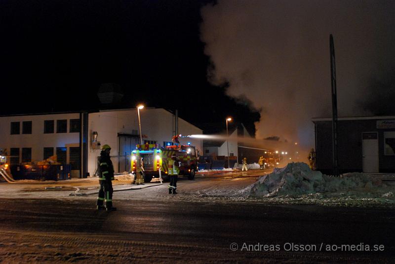 DSC_0114.JPG - Vid 01.30 larmades Räddningstjänsten från flera stationer samt ambulans och polis till Helsingborgsvägen i Ängelholm där man hade en fullt utvecklad brand i en byggnad som beräknas vara 30 meter bred och 100 meter lång, i byggnaden finns bland annat ett företag som sysslar med fyrverkerier och en bilverkstad. Så man vet inte om där finns gasolflaskor. En hel del fyrverkerier har smällt av. Man har ännu inte kontroll över branden då det även är svårt att få fram vatten eftersom brandposten har frusit fast. Ingen person ska ha skadats i branden.