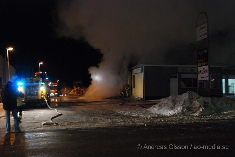 DSC_0118.JPG - Vid 01.30 larmades Räddningstjänsten från flera stationer samt ambulans och polis till Helsingborgsvägen i Ängelholm där man hade en fullt utvecklad brand i en byggnad som beräknas vara 30 meter bred och 100 meter lång, i byggnaden finns bland annat ett företag som sysslar med fyrverkerier och en bilverkstad. Så man vet inte om där finns gasolflaskor. En hel del fyrverkerier har smällt av. Man har ännu inte kontroll över branden då det även är svårt att få fram vatten eftersom brandposten har frusit fast. Ingen person ska ha skadats i branden.