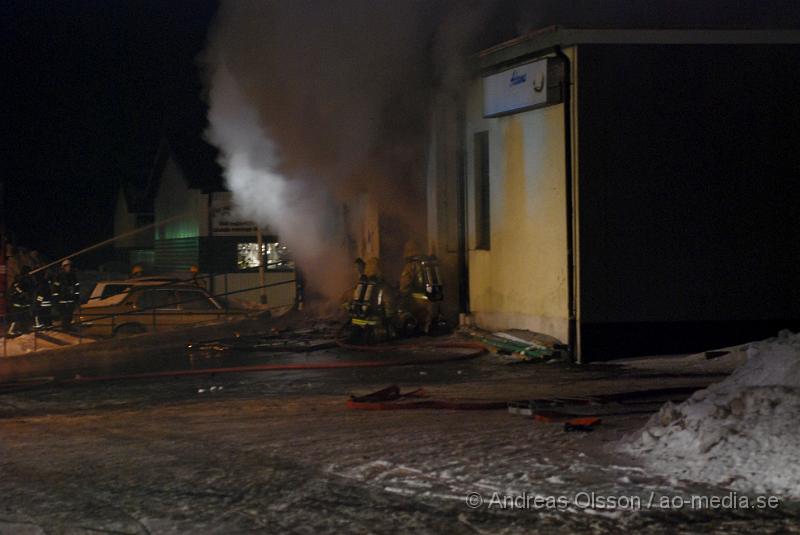 DSC_0120.JPG - Vid 01.30 larmades Räddningstjänsten från flera stationer samt ambulans och polis till Helsingborgsvägen i Ängelholm där man hade en fullt utvecklad brand i en byggnad som beräknas vara 30 meter bred och 100 meter lång, i byggnaden finns bland annat ett företag som sysslar med fyrverkerier och en bilverkstad. Så man vet inte om där finns gasolflaskor. En hel del fyrverkerier har smällt av. Man har ännu inte kontroll över branden då det även är svårt att få fram vatten eftersom brandposten har frusit fast. Ingen person ska ha skadats i branden.