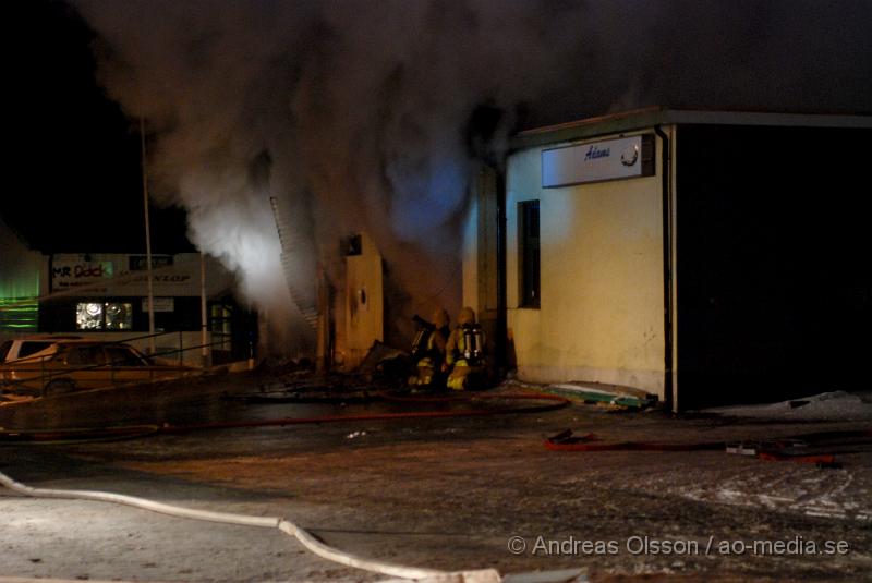 DSC_0123.JPG - Vid 01.30 larmades Räddningstjänsten från flera stationer samt ambulans och polis till Helsingborgsvägen i Ängelholm där man hade en fullt utvecklad brand i en byggnad som beräknas vara 30 meter bred och 100 meter lång, i byggnaden finns bland annat ett företag som sysslar med fyrverkerier och en bilverkstad. Så man vet inte om där finns gasolflaskor. En hel del fyrverkerier har smällt av. Man har ännu inte kontroll över branden då det även är svårt att få fram vatten eftersom brandposten har frusit fast. Ingen person ska ha skadats i branden.