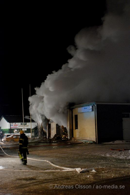 DSC_0136.JPG - Vid 01.30 larmades Räddningstjänsten från flera stationer samt ambulans och polis till Helsingborgsvägen i Ängelholm där man hade en fullt utvecklad brand i en byggnad som beräknas vara 30 meter bred och 100 meter lång, i byggnaden finns bland annat ett företag som sysslar med fyrverkerier och en bilverkstad. Så man vet inte om där finns gasolflaskor. En hel del fyrverkerier har smällt av. Man har ännu inte kontroll över branden då det även är svårt att få fram vatten eftersom brandposten har frusit fast. Ingen person ska ha skadats i branden.