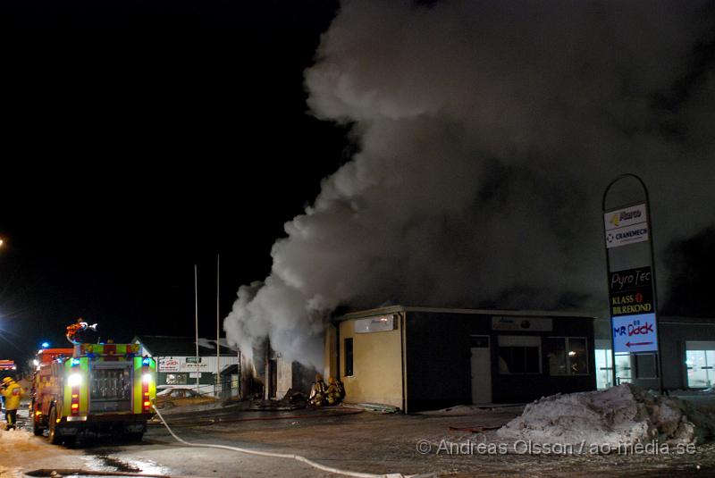 DSC_0141.JPG - Vid 01.30 larmades Räddningstjänsten från flera stationer samt ambulans och polis till Helsingborgsvägen i Ängelholm där man hade en fullt utvecklad brand i en byggnad som beräknas vara 30 meter bred och 100 meter lång, i byggnaden finns bland annat ett företag som sysslar med fyrverkerier och en bilverkstad. Så man vet inte om där finns gasolflaskor. En hel del fyrverkerier har smällt av. Man har ännu inte kontroll över branden då det även är svårt att få fram vatten eftersom brandposten har frusit fast. Ingen person ska ha skadats i branden.