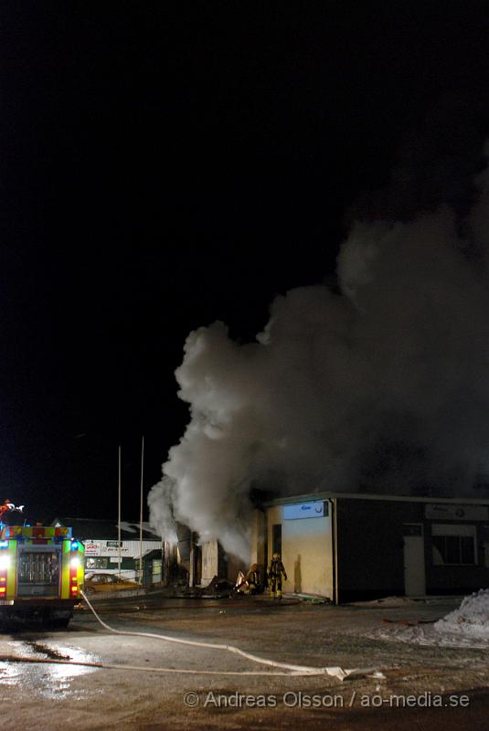 DSC_0142.JPG - Vid 01.30 larmades Räddningstjänsten från flera stationer samt ambulans och polis till Helsingborgsvägen i Ängelholm där man hade en fullt utvecklad brand i en byggnad som beräknas vara 30 meter bred och 100 meter lång, i byggnaden finns bland annat ett företag som sysslar med fyrverkerier och en bilverkstad. Så man vet inte om där finns gasolflaskor. En hel del fyrverkerier har smällt av. Man har ännu inte kontroll över branden då det även är svårt att få fram vatten eftersom brandposten har frusit fast. Ingen person ska ha skadats i branden.