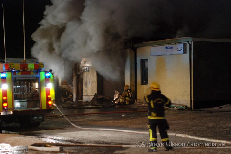 DSC_0146.JPG - Vid 01.30 larmades Räddningstjänsten från flera stationer samt ambulans och polis till Helsingborgsvägen i Ängelholm där man hade en fullt utvecklad brand i en byggnad som beräknas vara 30 meter bred och 100 meter lång, i byggnaden finns bland annat ett företag som sysslar med fyrverkerier och en bilverkstad. Så man vet inte om där finns gasolflaskor. En hel del fyrverkerier har smällt av. Man har ännu inte kontroll över branden då det även är svårt att få fram vatten eftersom brandposten har frusit fast. Ingen person ska ha skadats i branden.