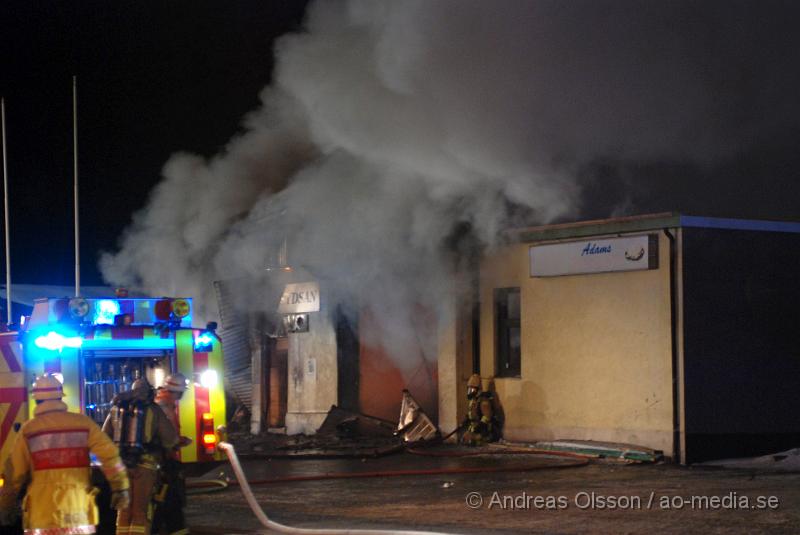 DSC_0155.JPG - Vid 01.30 larmades Räddningstjänsten från flera stationer samt ambulans och polis till Helsingborgsvägen i Ängelholm där man hade en fullt utvecklad brand i en byggnad som beräknas vara 30 meter bred och 100 meter lång, i byggnaden finns bland annat ett företag som sysslar med fyrverkerier och en bilverkstad. Så man vet inte om där finns gasolflaskor. En hel del fyrverkerier har smällt av. Man har ännu inte kontroll över branden då det även är svårt att få fram vatten eftersom brandposten har frusit fast. Ingen person ska ha skadats i branden.