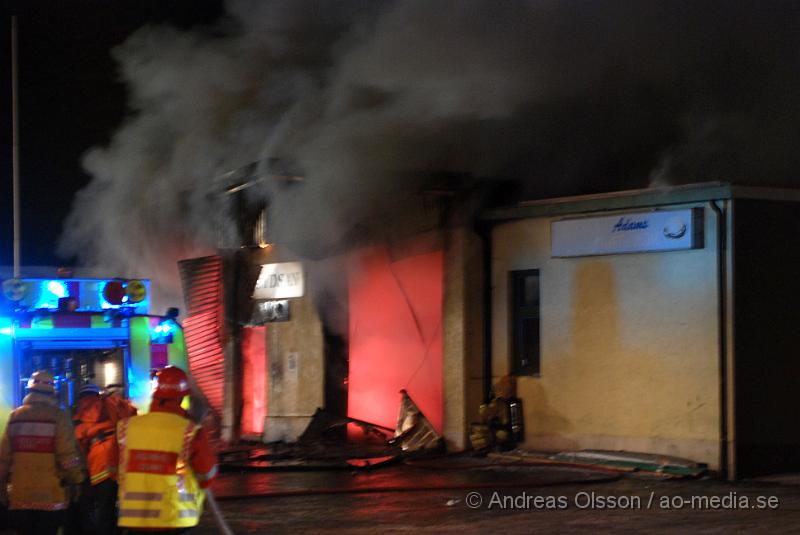 DSC_0161.JPG - Vid 01.30 larmades Räddningstjänsten från flera stationer samt ambulans och polis till Helsingborgsvägen i Ängelholm där man hade en fullt utvecklad brand i en byggnad som beräknas vara 30 meter bred och 100 meter lång, i byggnaden finns bland annat ett företag som sysslar med fyrverkerier och en bilverkstad. Så man vet inte om där finns gasolflaskor. En hel del fyrverkerier har smällt av. Man har ännu inte kontroll över branden då det även är svårt att få fram vatten eftersom brandposten har frusit fast. Ingen person ska ha skadats i branden.