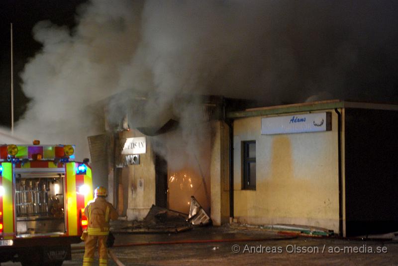 DSC_0164.JPG - Vid 01.30 larmades Räddningstjänsten från flera stationer samt ambulans och polis till Helsingborgsvägen i Ängelholm där man hade en fullt utvecklad brand i en byggnad som beräknas vara 30 meter bred och 100 meter lång, i byggnaden finns bland annat ett företag som sysslar med fyrverkerier och en bilverkstad. Så man vet inte om där finns gasolflaskor. En hel del fyrverkerier har smällt av. Man har ännu inte kontroll över branden då det även är svårt att få fram vatten eftersom brandposten har frusit fast. Ingen person ska ha skadats i branden.