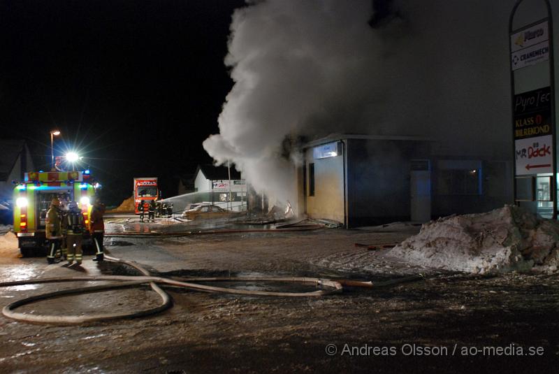 DSC_0176.JPG - Vid 01.30 larmades Räddningstjänsten från flera stationer samt ambulans och polis till Helsingborgsvägen i Ängelholm där man hade en fullt utvecklad brand i en byggnad som beräknas vara 30 meter bred och 100 meter lång, i byggnaden finns bland annat ett företag som sysslar med fyrverkerier och en bilverkstad. Så man vet inte om där finns gasolflaskor. En hel del fyrverkerier har smällt av. Man har ännu inte kontroll över branden då det även är svårt att få fram vatten eftersom brandposten har frusit fast. Ingen person ska ha skadats i branden.