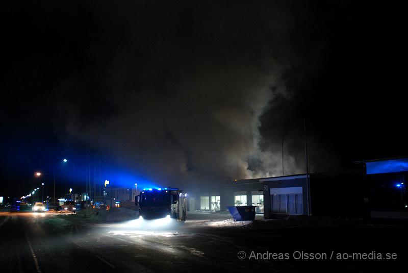 DSC_0183.JPG - Vid 01.30 larmades Räddningstjänsten från flera stationer samt ambulans och polis till Helsingborgsvägen i Ängelholm där man hade en fullt utvecklad brand i en byggnad som beräknas vara 30 meter bred och 100 meter lång, i byggnaden finns bland annat ett företag som sysslar med fyrverkerier och en bilverkstad. Så man vet inte om där finns gasolflaskor. En hel del fyrverkerier har smällt av. Man har ännu inte kontroll över branden då det även är svårt att få fram vatten eftersom brandposten har frusit fast. Ingen person ska ha skadats i branden.